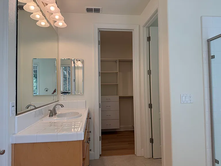 In-suite bathroom with 2 sinks, a whirlpool bathtub, a shower stall with glass enclosure and a second walk-in closet.