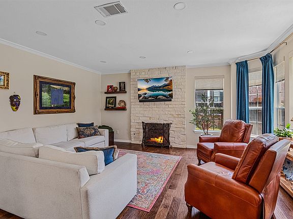 Living area featuring wood-finish flooring, a stone-clad fireplace, recessed lighting, and crown molding