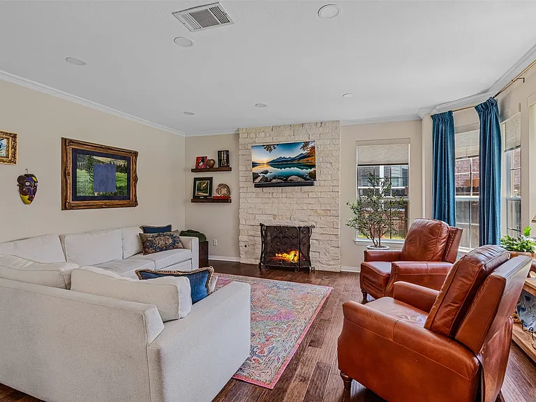 Living area featuring wood-finish flooring, a stone-clad fireplace, recessed lighting, and crown molding