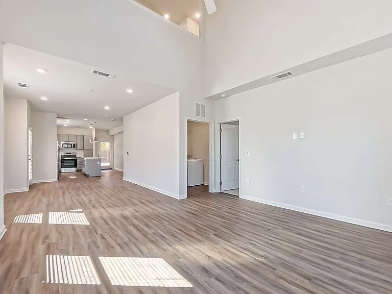 Bright and airy open-concept living space with high ceilings, contemporary kitchen, and stylish wood flooring.