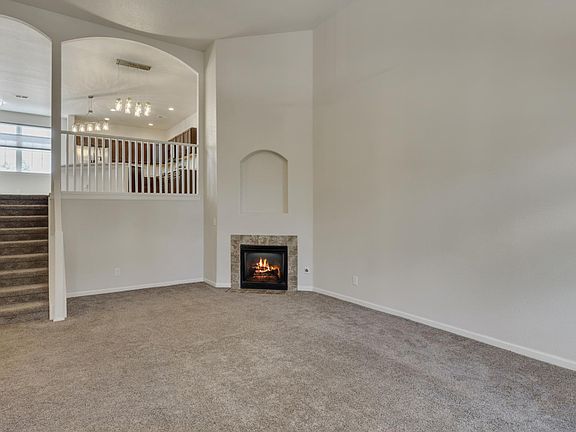 POV 2 - Casa Bonita's spacious living room has vaulted ceilings, in-wall speakers, bay windows, a large ceiling fan with clear blades, high pile plush carpet, and a gas heater.