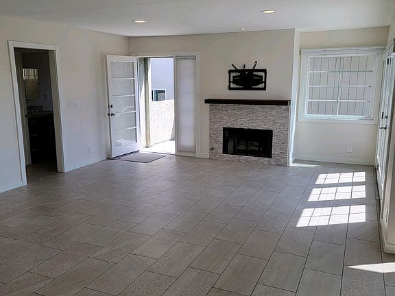 Living room with French doors to front deck, gas fireplace with large screen tv mount and recessed lighting on dimmers.