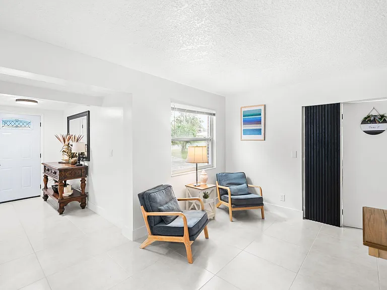 Open entry sitting area with tile flooring, front window, and space for a small lounge or reading nook.