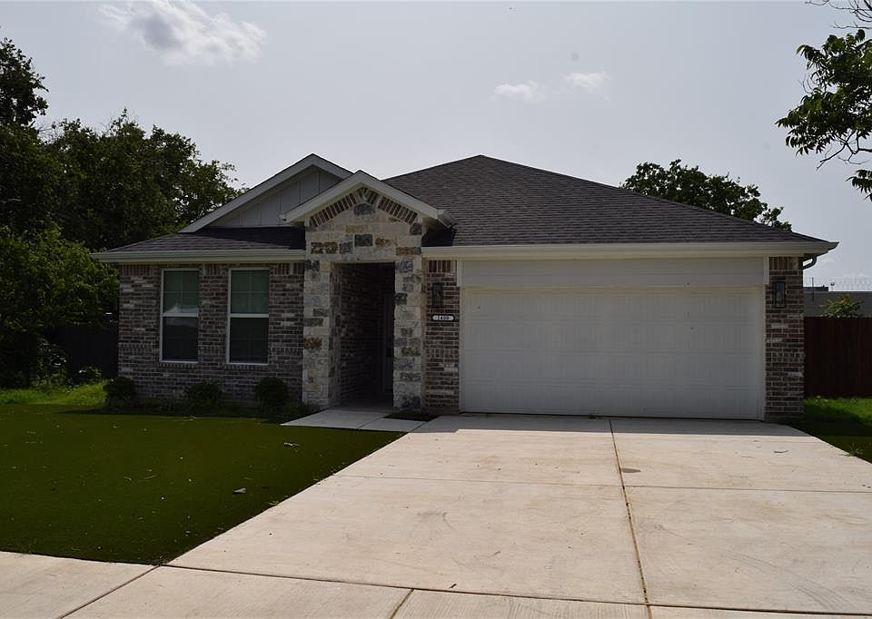 View of front of property featuring a garage, driveway, a front yard, brick siding, and a shingled roof