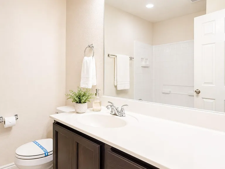 Clean bathroom with a wide vanity, large mirror, and shower/tub combo with tiled surround for easy upkeep.