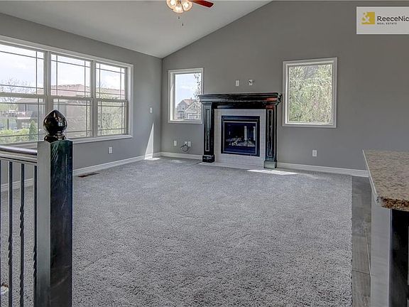 Custom tiled gas fireplace with stained mantel, large windows and ceiling fan in great room. Square metal stair spindles in choice of black or oil rubbed bronze.