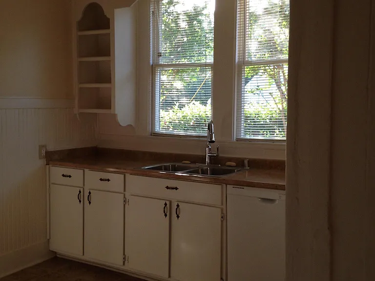 Iconic hand crafted open space cabinets, tall ceilings with spaces for display of lovely kitchen charm and storage space. Porcelain tiled flooring, view of private side garden. The kitchen includes quiet dishwasher, pull down hand held spray faucet and do