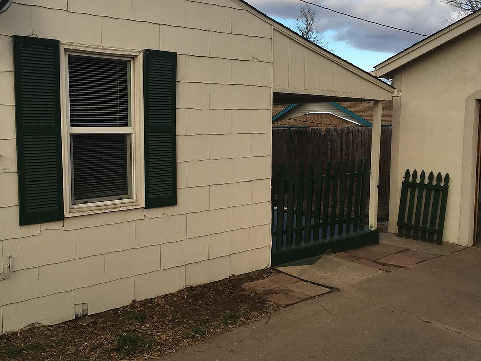Exterior from driveway off alley. Entrance is through the green gate. Small porch and small yard for gardening if that's an interest. Off street parking spot is just off camera to the right.