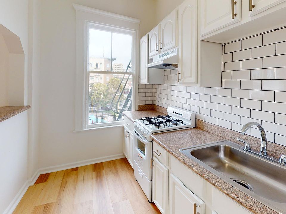 Kitchen with multiple cabinets, stove, range hood, and sink