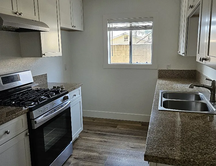 kitchen with gas stove, nice countertops, sink, and wood floors