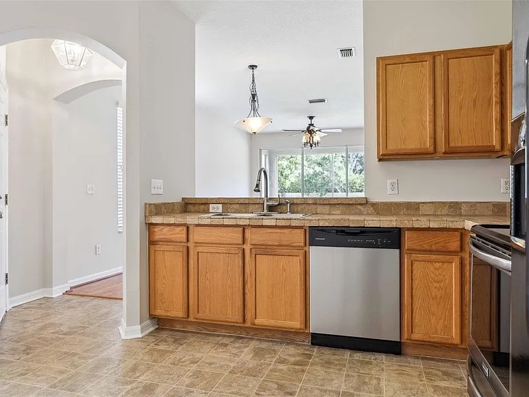 Kitchen has been updated with white cabinets and black handles, track lighting, and a stainless steel refrigerator