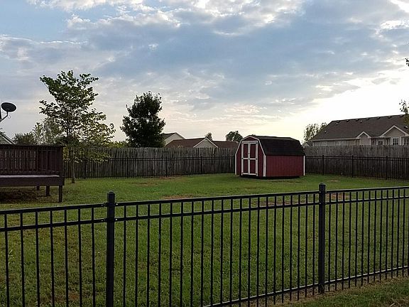 Fenced in backyard with deck and storage building