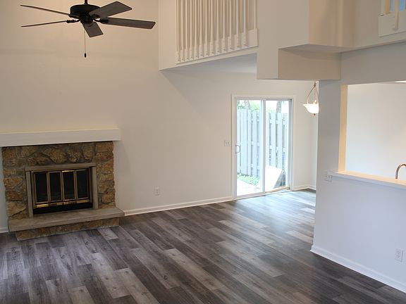 All new LVP flooring, paint and ceiling fan in living room with wood burning fireplace. Sliders from dining area to enclosed concrete patio