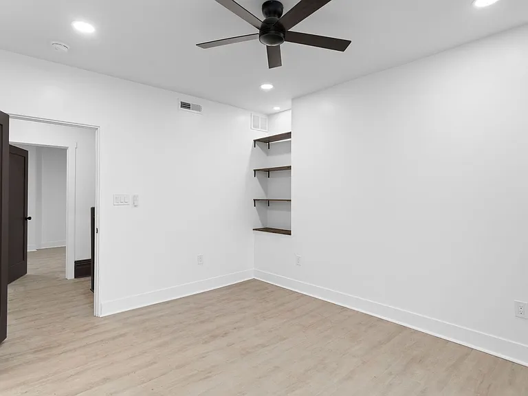 Second bedroom with ceiling fan and custom built-in shelving