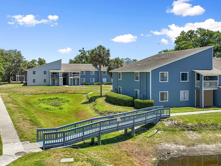 Charming blue apartment buildings with modern design, surrounded by lush greenery and scenic pathways.
