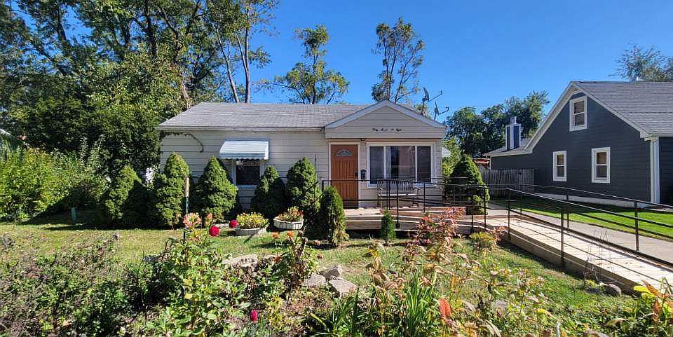 Street view of the house, large front yard, garden bed custom built wood deck, ramp and railings