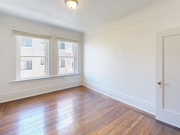 Spacious bedroom with wood-like flooring and a large window offering natural light