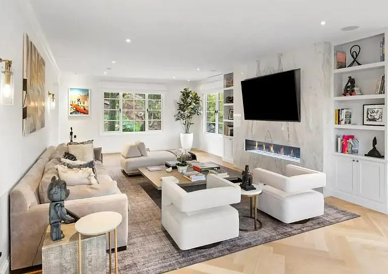 Comfort and entertainment are amplified by art work, technology and a warm fire in this spacious living room.