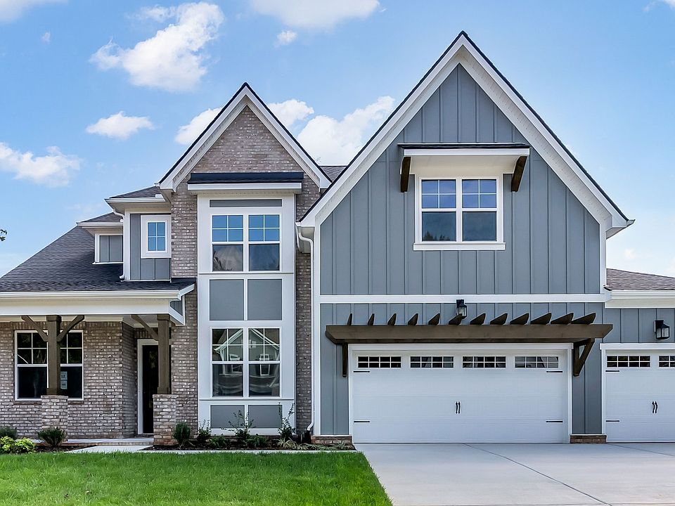 Elegant gray house with gabled roof and brick facade. Enjoy serene Brush Creek surroundings.