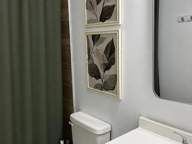 Bathroom with a vanity sink, wall mirror, and tub/shower combo with curtain and wood-look tile surround.