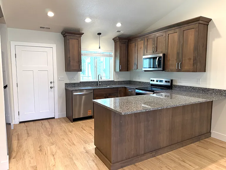 Spacious kitchen with stainless steel microwave, stove, fridge and dishwasher. Access to the patio.