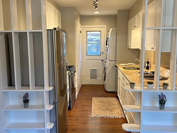 Kitchen with pantry closet and new full-size stack washer and dryer. Door to back yard.