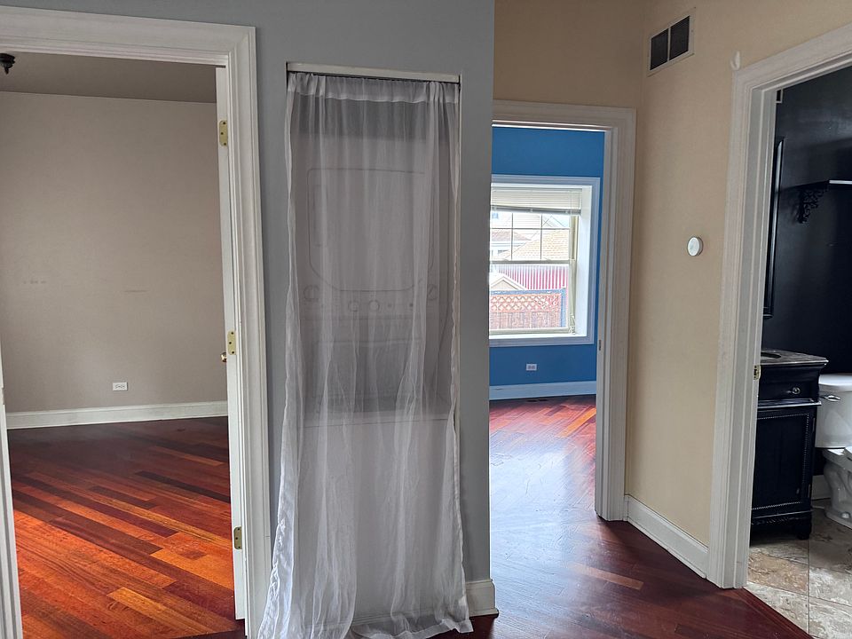 View into the bathroom and bedrooms from the living room. Behind the curtain is stacked washer/dryer