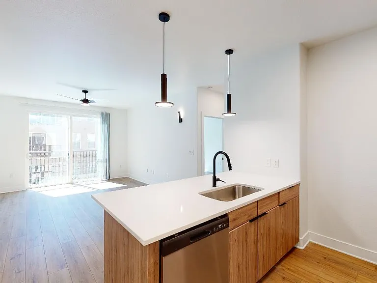 Apartment kitchen with stainless steel appliances, quartz countertops and wood-style flooring.