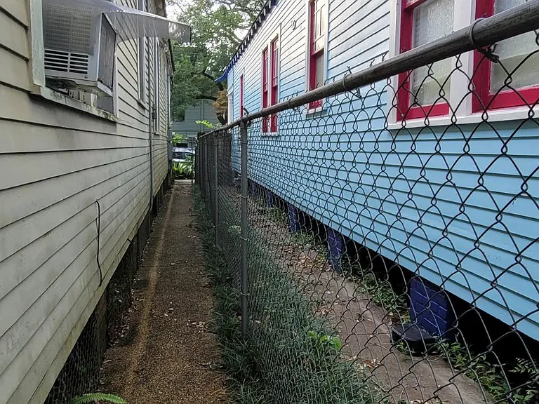 Looking from apartment door to street. Locked gate at end.