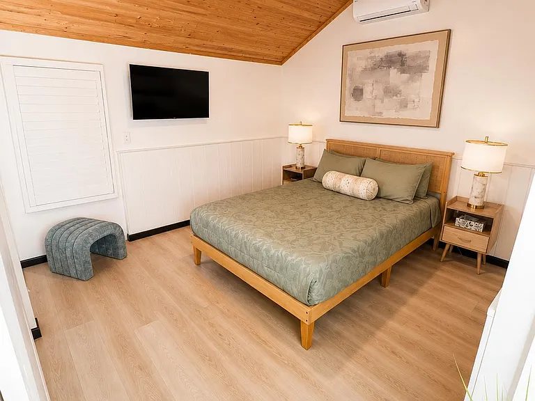 Vaulted wood ceiling bedroom with queen bed, split A/C, ceiling fan, and nightstands for convenient everyday living.