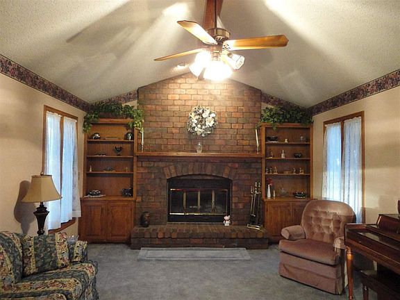 View of living room with full wall brick fireplace with insert