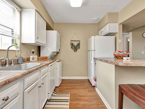 Spacious Kitchen with Ample Counter Space and Stacked Laundry Machines at The Commons Student Apartments in Oxford, OH