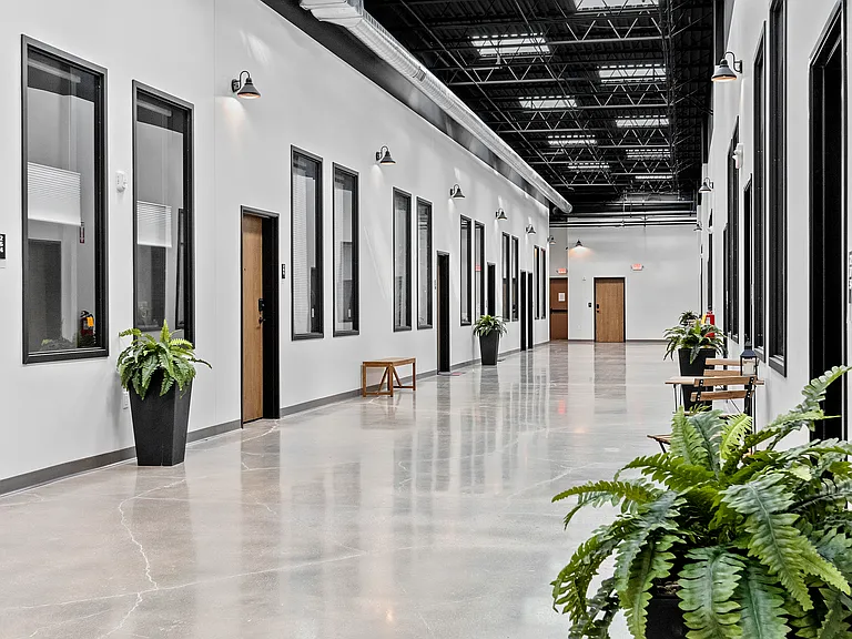 Hallways? More like hangout zones. 16 feet wide, flooded with sunshine, and set with bistro tables and ferns.