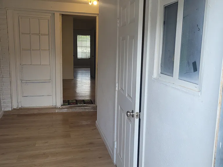 View of hallway from the back entrance, bedroom (right door) and kitchen/dining space (central door)