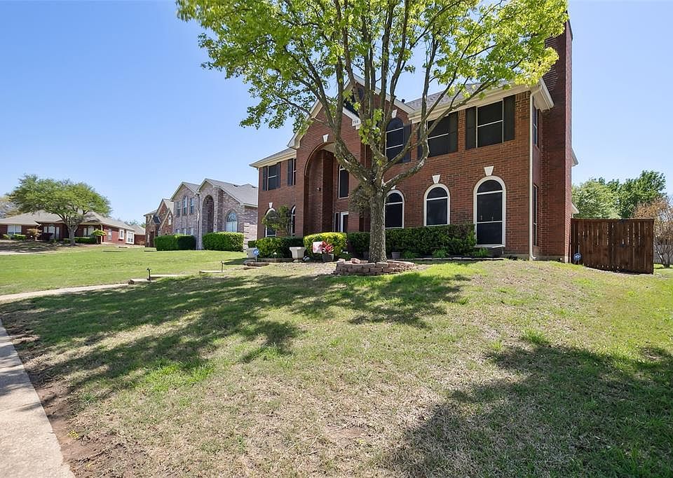View of front of house with brick siding, a front lawn, and fence