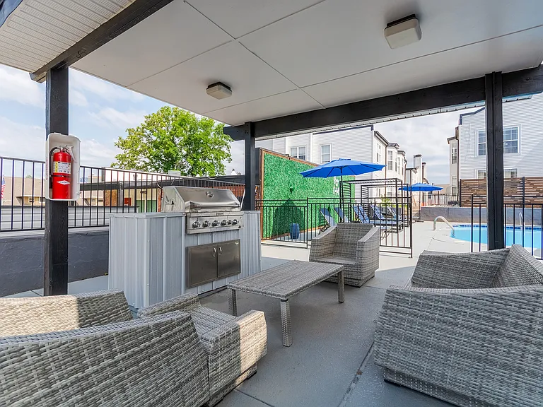 A gas grill with comfortable seating area is shown overlooking the sparkling pool and sundeck at ReNew on Cantrell.