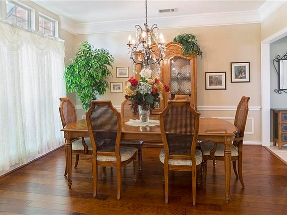 The formal dining room with engineered hardwood floors, crown molding, a chair rail, and picture frame molding beneath the chair rail.  The windows on the left look out on the landscaped front yard.  The doorway to the right leads to the kitchen.