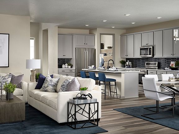 A modern and spacious open-concept kitchen and living room with white cabinets, stainless steel appl