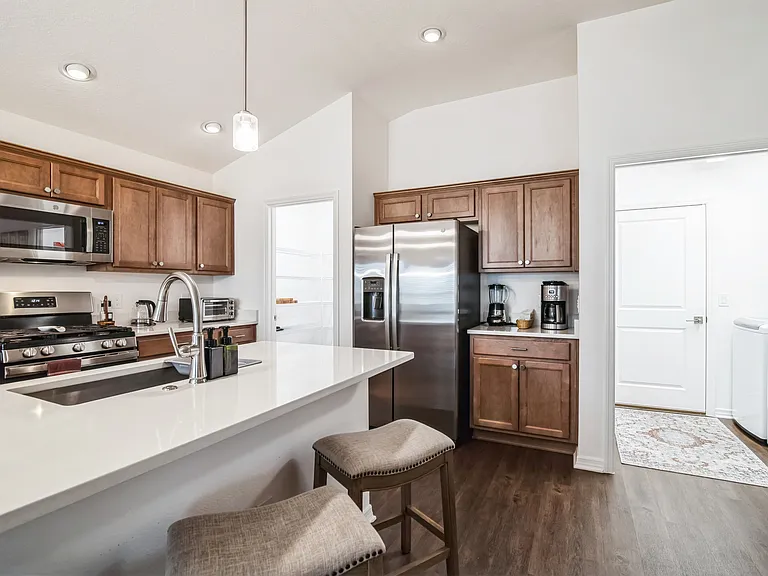 The Kitchen has a view of Cabinets, a Refrigerator, a Microwave, a Stove, and an Island with a Kitchen and Bar Siting Area.