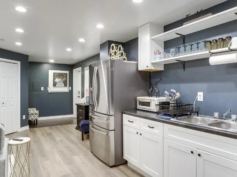 Updated kitchen with stainless-steel refrigerator, ample counter space, open shelving, and recessed lighting.