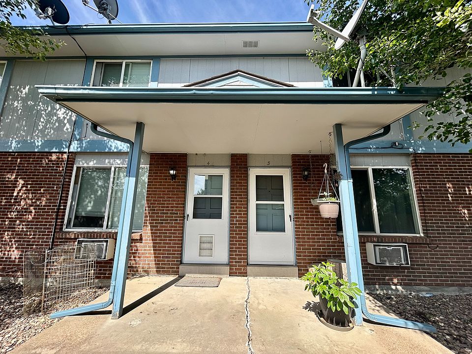Charming townhouse entrance with a brick facade, elegant blue trim, and inviting porch area.