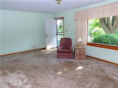 Very large living room, carpet & large picture window with a view of the mature trees & landscaped yard.