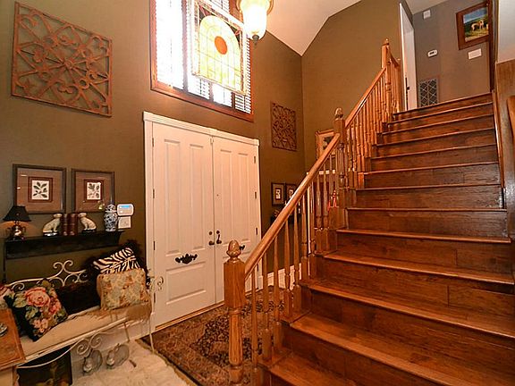 Elegant entry offering terrazzo tile floors, two story high ceilings, half bath and a wooden stairwa