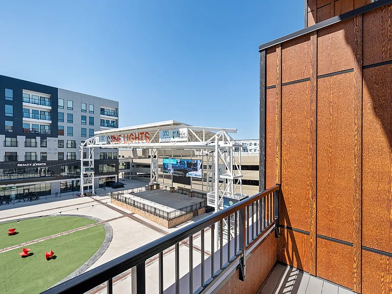 Modern apartment balcony overlooking a vibrant urban plaza with green space and public seating, perfect for city views and lifestyle amenities. Modern apartment balcony overlooking a vibrant urban plaza with green space and public seating, perfect for cit