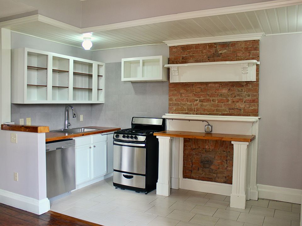 Cozy kitchen with tile floor and back splash, exposed brick and wooden countertops.