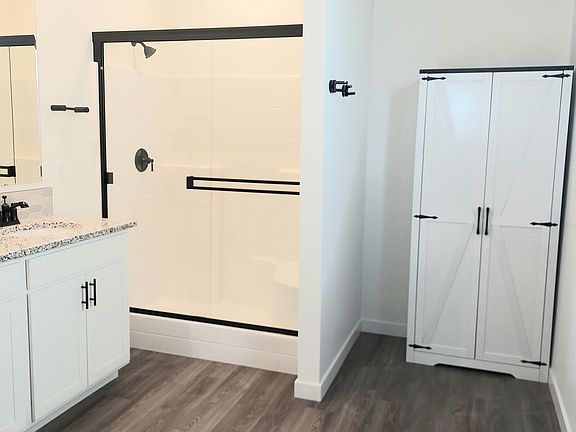 Primary bathroom with double sinks, shower with bench and linen cabinet.