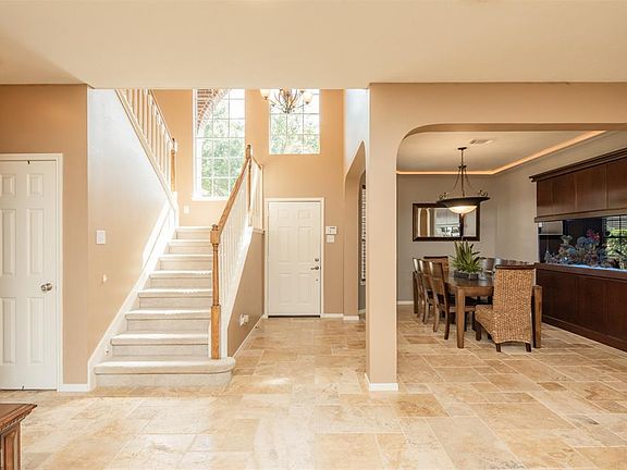 Light and bright with 2 grand arched windows, the entry way is so inviting! There are travertine tile floors through out living area, kitchen and entry. There are custom cabinets for the 160 gallon salt water fish tank and spacious dining room. The f