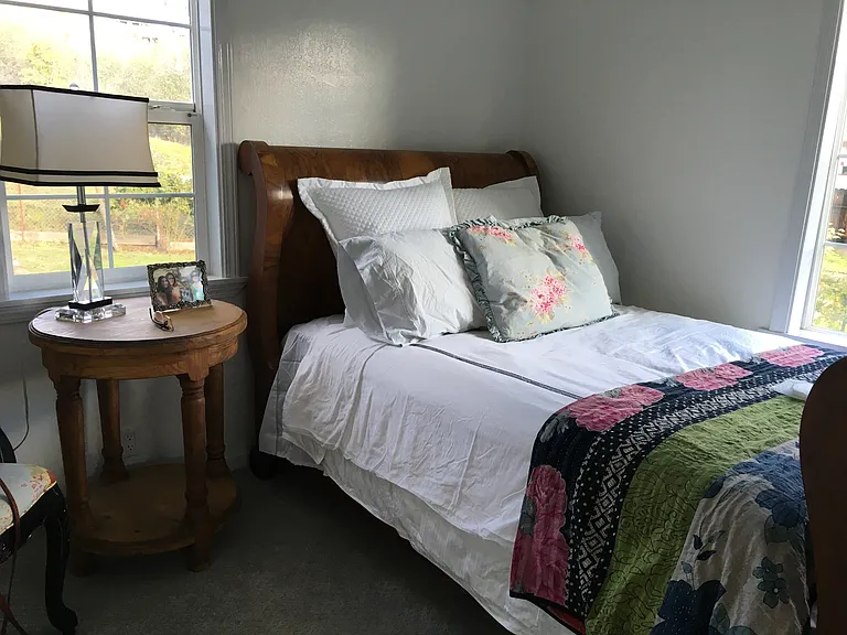 Bedroom off sunroom has an electric matte black fireplace stove