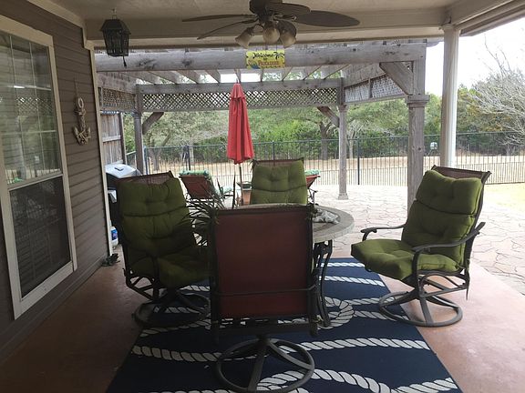Covered patio steps down to huge tiled area with arbor. 