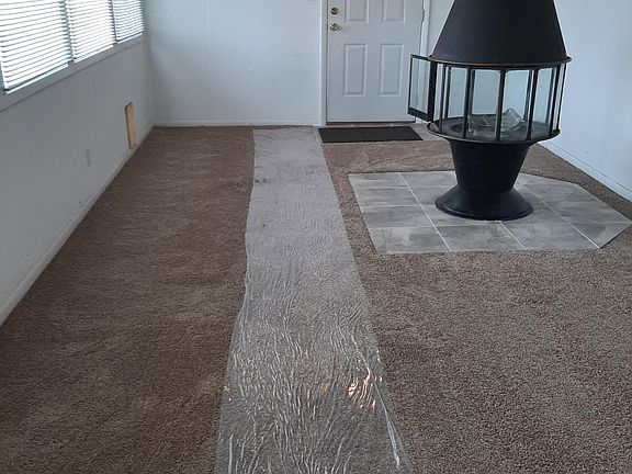 Another view of family room and fireplace, from south end of room. The back door in this photo exits onto small covered porch area, inside fenced/gated area of yard.